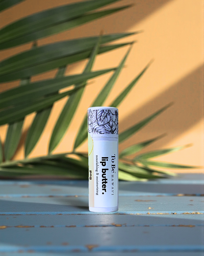 Lip balm tube in the flavor POG with decorative label on a textured surface with green leaves in the background